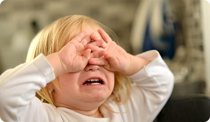 Toddler crying with hands on face